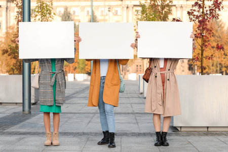Beautiful young women with blank posters outdoorsの写真素材