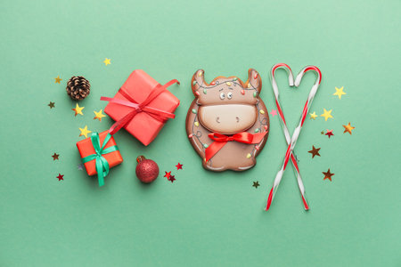 Tasty cookie in shape of bull and Christmas decor on color backgroundの写真素材