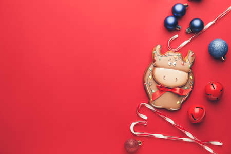 Tasty cookie in shape of bull and Christmas decor on color backgroundの写真素材