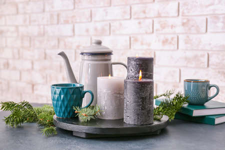 Beautiful aroma candles with tea and fir tree branches on tableの写真素材