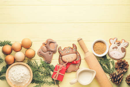 Tasty Christmas cookies in shape of bull and ingredients on tableの写真素材