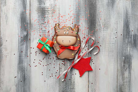 Tasty cookie in shape of bull, gift and Christmas decor on wooden backgroundの写真素材