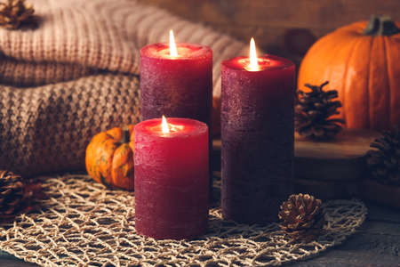 Beautiful aroma candles with autumn decor on tableの写真素材