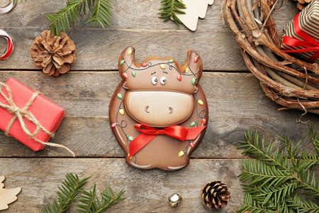 Tasty cookie in shape of bull and Christmas decor on wooden backgroundの写真素材