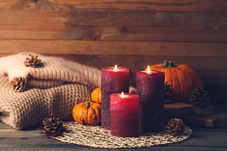 Beautiful aroma candles with autumn decor on tableの写真素材