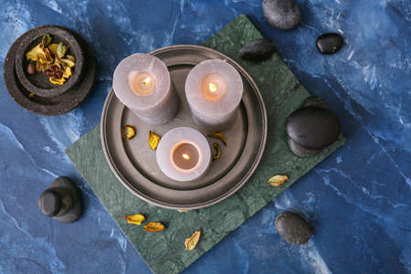 Beautiful aroma candles with spa stones on color backgroundの写真素材