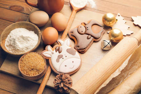 Tasty Christmas cookies in shape of bull and ingredients on tableの写真素材