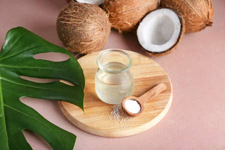 Jar of coconut oil and spoon with flakes on color backgroundの写真素材