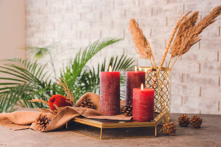 Beautiful aroma candles with Christmas decor on tableの写真素材