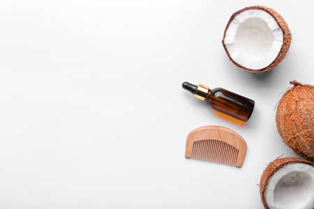 Composition with bottle of coconut oil and comb on white background