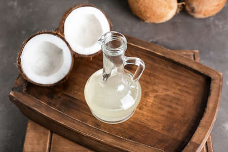 Tray with decanter of coconut oil on dark background