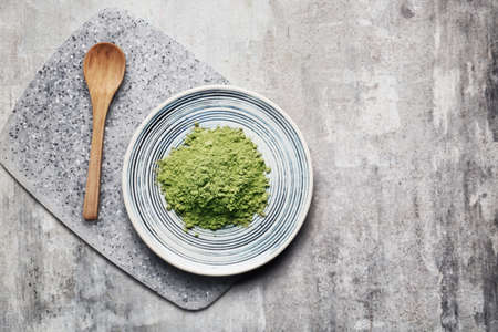 Plate with powdered matcha tea and spoon on dark backgroundの写真素材