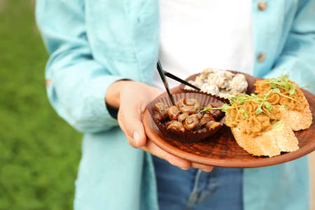 Woman with different snail dishes on plate outdoorsの写真素材
