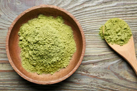 Bowl and spoon with powdered matcha tea on wooden backgroundの写真素材