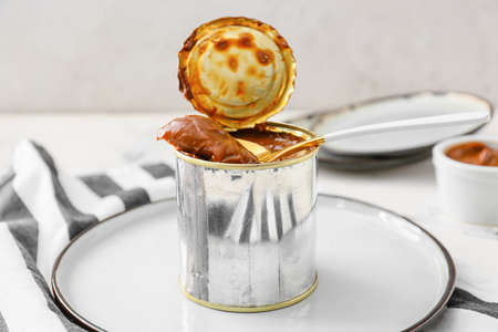 Tin can of boiled condensed milk on light backgroundの写真素材