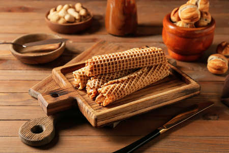 Tasty wafer rolls with boiled condensed milk on wooden backgroundの写真素材