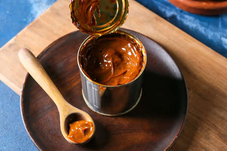 Tin can of boiled condensed milk on color backgroundの写真素材