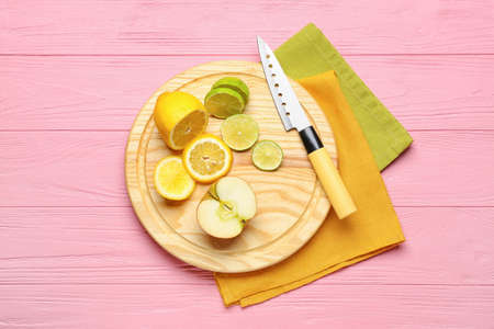 Cutting board and cut fruits on color wooden backgroundの写真素材