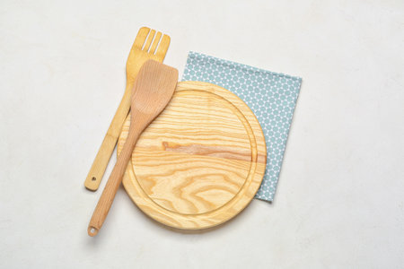 Wooden cutting board and kitchen utensils on light backgroundの写真素材
