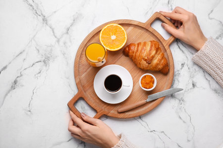 Woman holding wooden tray with tasty breakfast on light backgroundの写真素材
