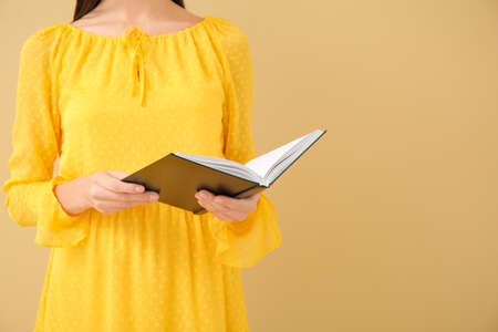 Young woman reading book on color backgroundの写真素材
