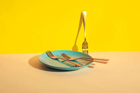Stylish forks and plate on color background
