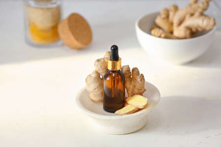 Bottle with ginger essential oil on light backgroundの写真素材