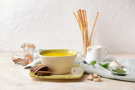 Bowl with tasty garlic cream soup on light backgroundの写真素材