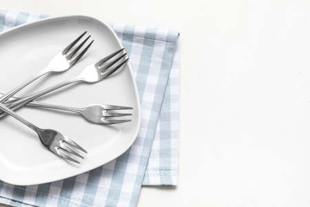Stylish forks and plate on white backgroundの写真素材