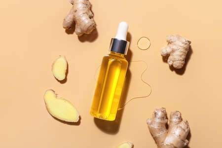 Bottle with ginger essential oil on color backgroundの写真素材
