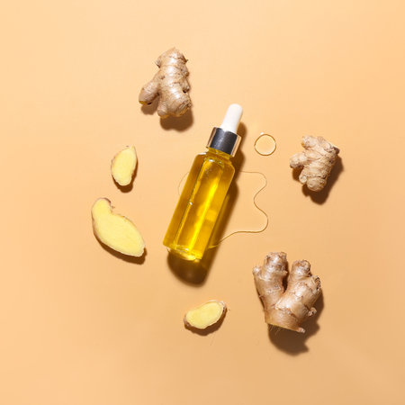 Bottle with ginger essential oil on color backgroundの写真素材