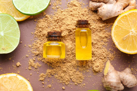 Bottle with ginger essential oil and citruses on color backgroundの写真素材
