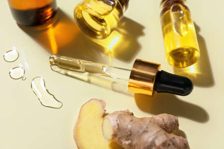 Bottles with ginger essential oil on color backgroundの写真素材