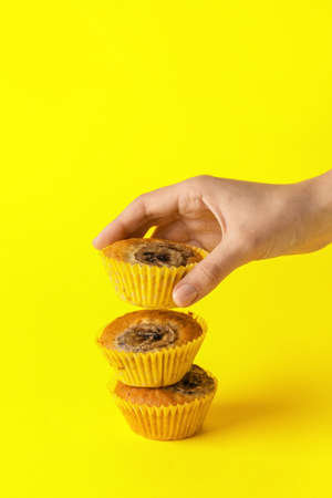 Female hand with tasty banana muffins on color backgroundの写真素材
