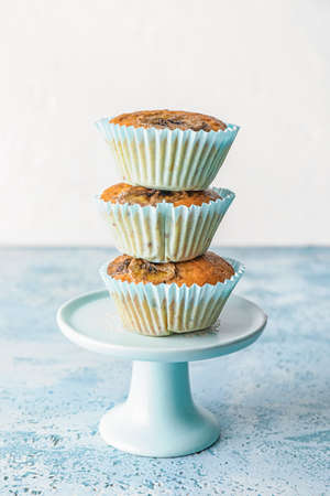 Dessert stand with tasty banana muffins on color tableの写真素材