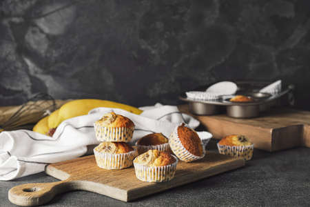 Board with tasty banana muffins on dark backgroundの写真素材