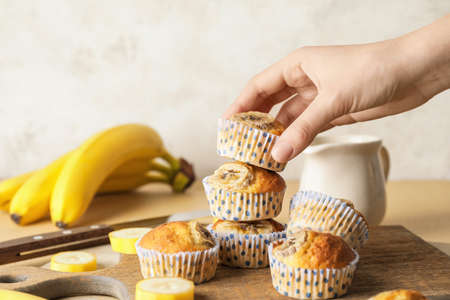 Female hand with tasty banana muffins on color tableの写真素材
