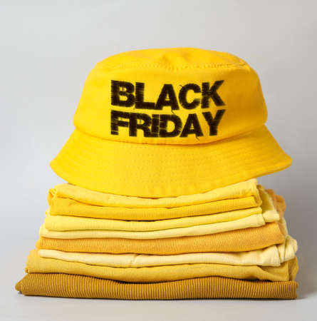 Stack of stylish clothes and hat with text BLACK FRIDAY on gray backgroundの写真素材