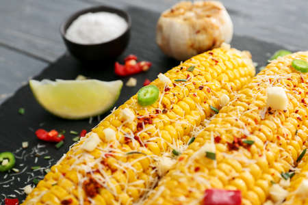Tasty baked corn cobs on dark backgroundの写真素材