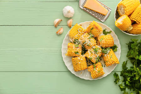 Plate with tasty baked corn cobs on color wooden backgroundの写真素材
