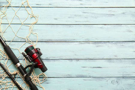Modern spinning rod and fish net on color wooden backgroundの写真素材