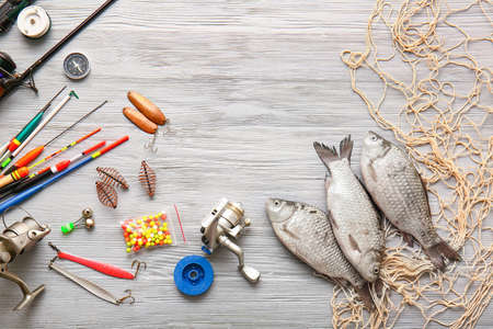 Different fishing equipment and fish on light wooden backgroundの写真素材