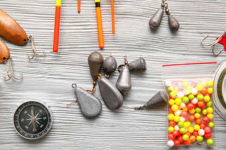 Different fishing equipment on light wooden background