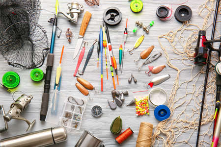Different fishing equipment on light wooden background