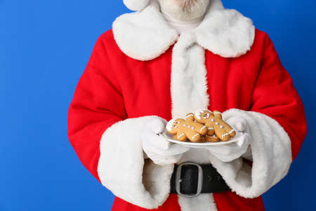 Santa Claus with tasty gingerbread cookies on color backgroundの写真素材
