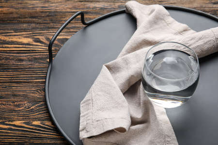 Modern tray with water on wooden background, closeup