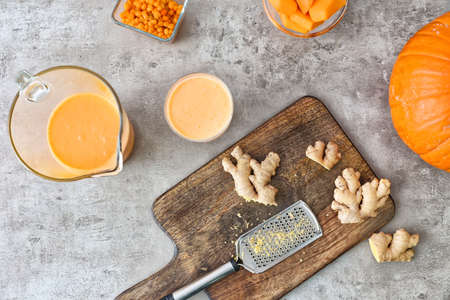 Tasty pumpkin smoothie with ingredients on gray background