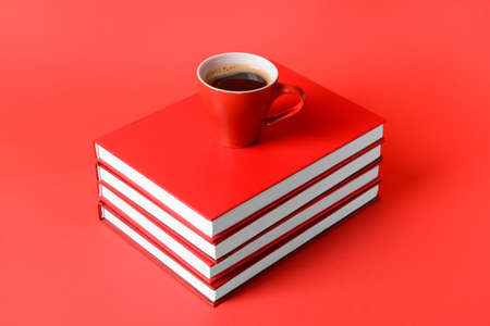 Blank books and cup of coffee on color backgroundの写真素材