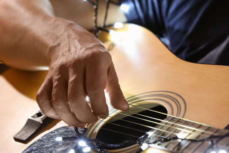Man playing guitar on Christmas eve, closeup