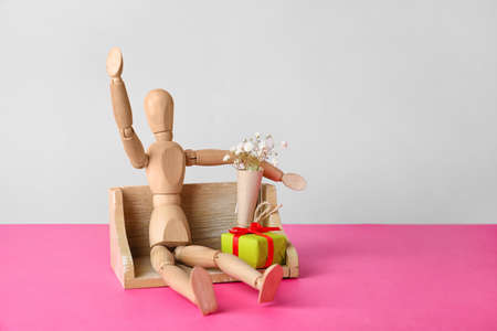 Wooden mannequin with gift box on color backgroundの写真素材